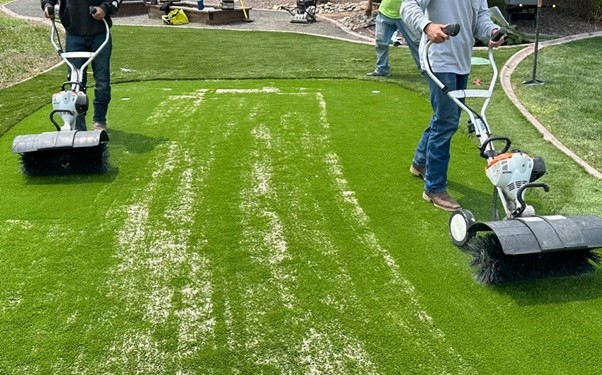 two person mowing artificial grass yard
